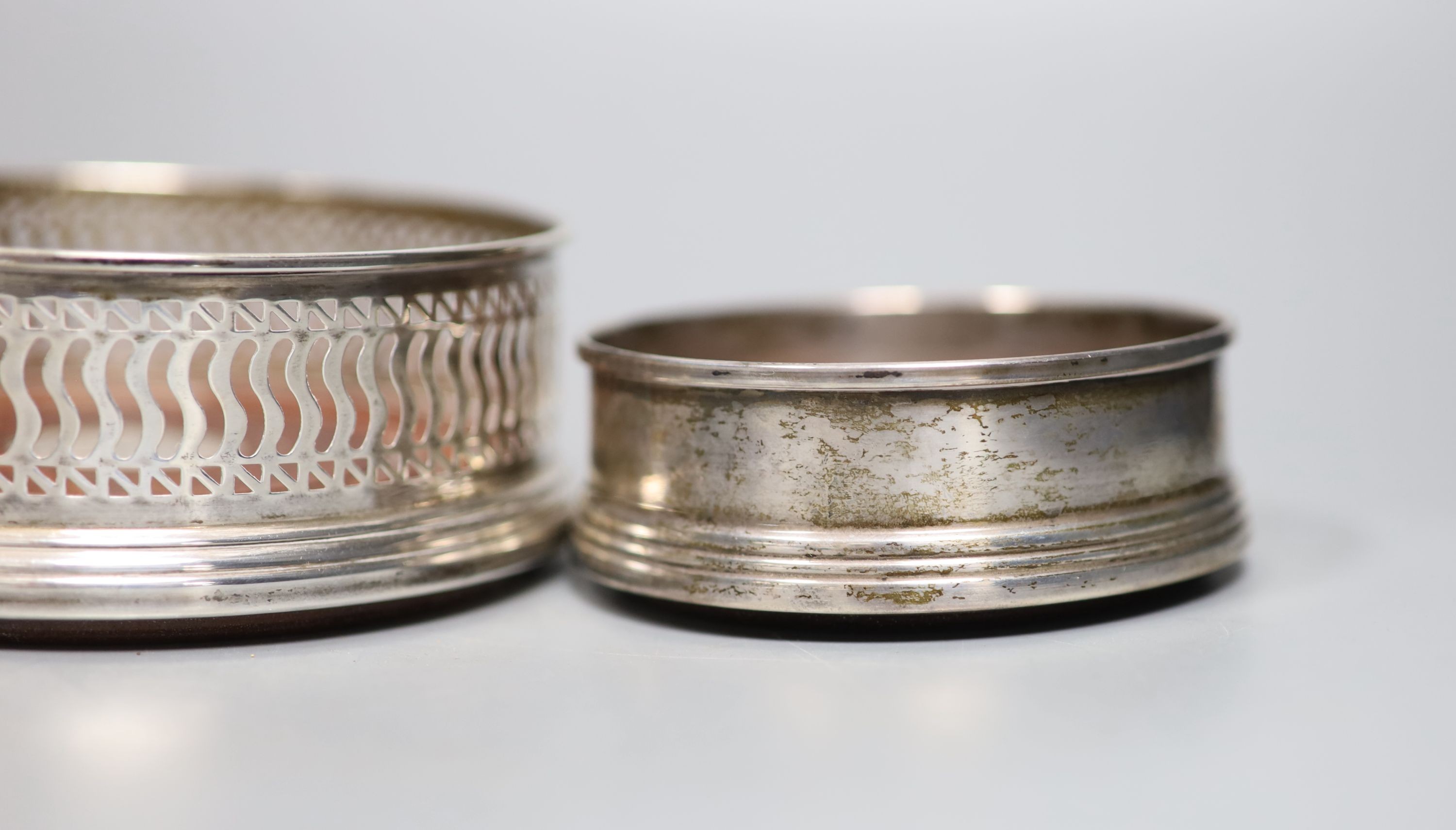 Four assorted modern silver mounted wine coasters, largest diameter 12.2cm.